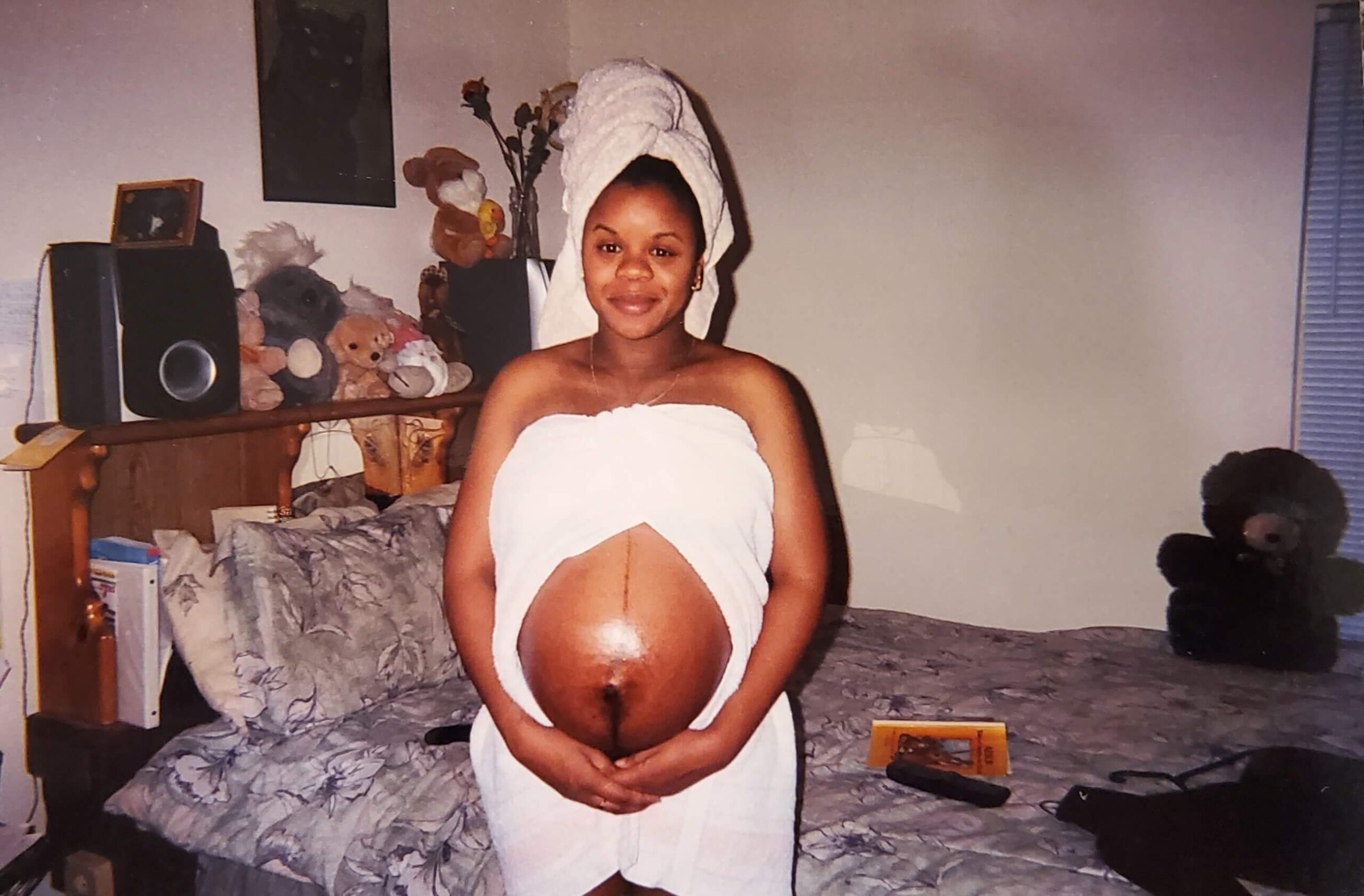 Certified love coach Shay 'Your Love Diva' standing in a bedroom with her pregnant belly exposed