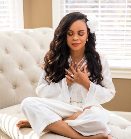 Certified love coach Shay 'Your Love Diva' sitting with hands crossed over chest meditating
